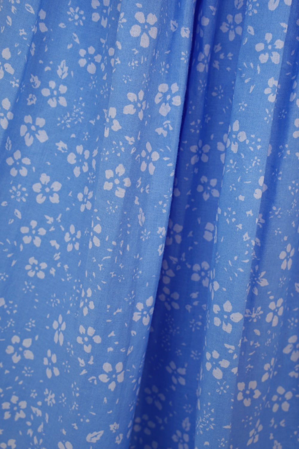 Close up of blue cotton fabric with white ditsy floral print
