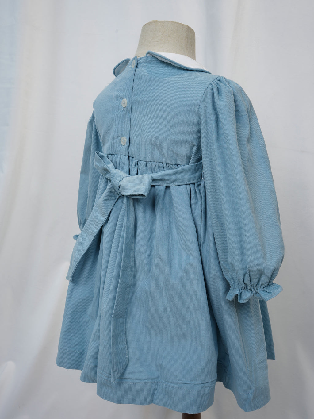 Back view with buttons and sash on blue hand smocked dress