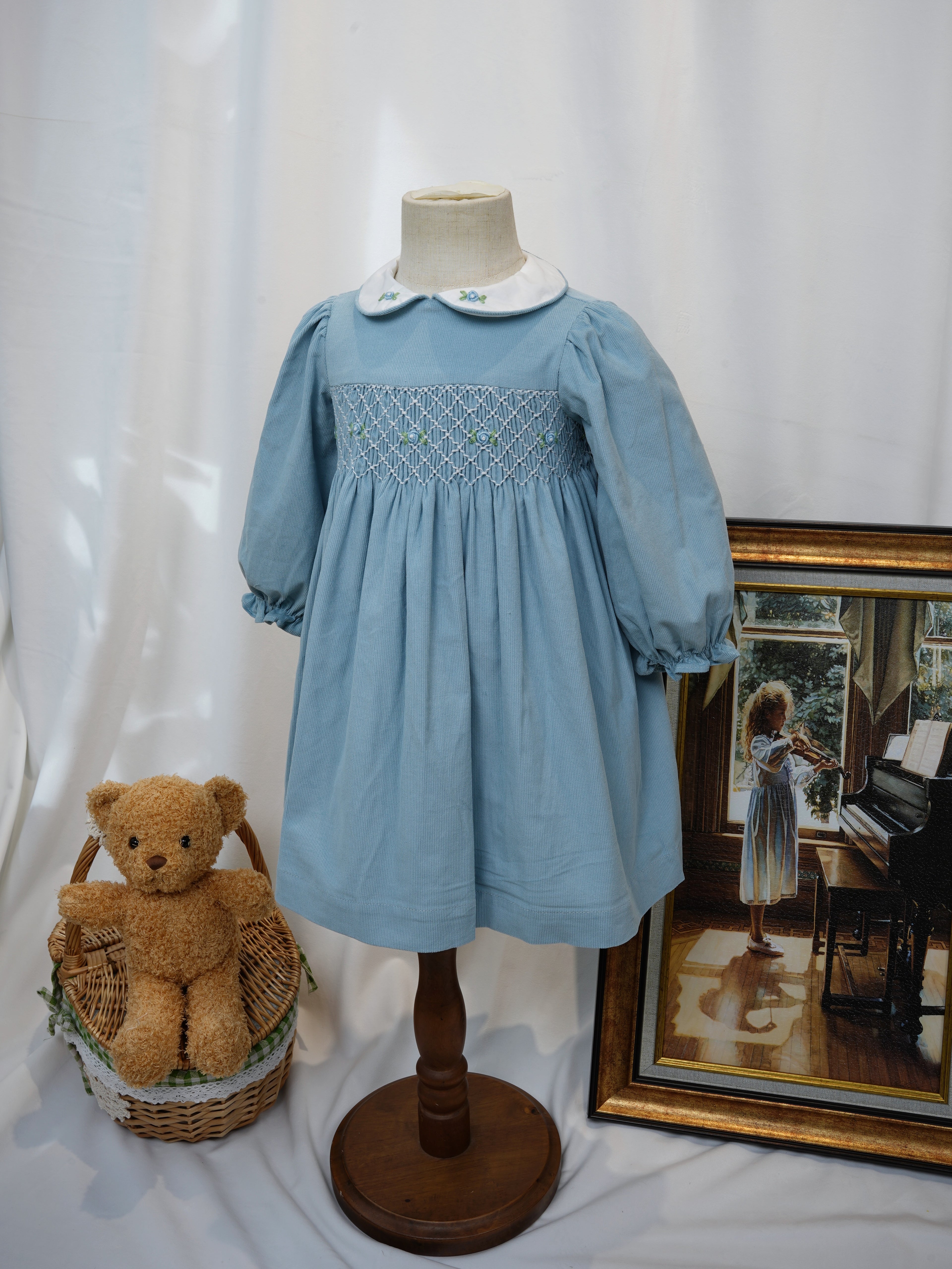 Angled front view of blue hand smocked long sleeve dress