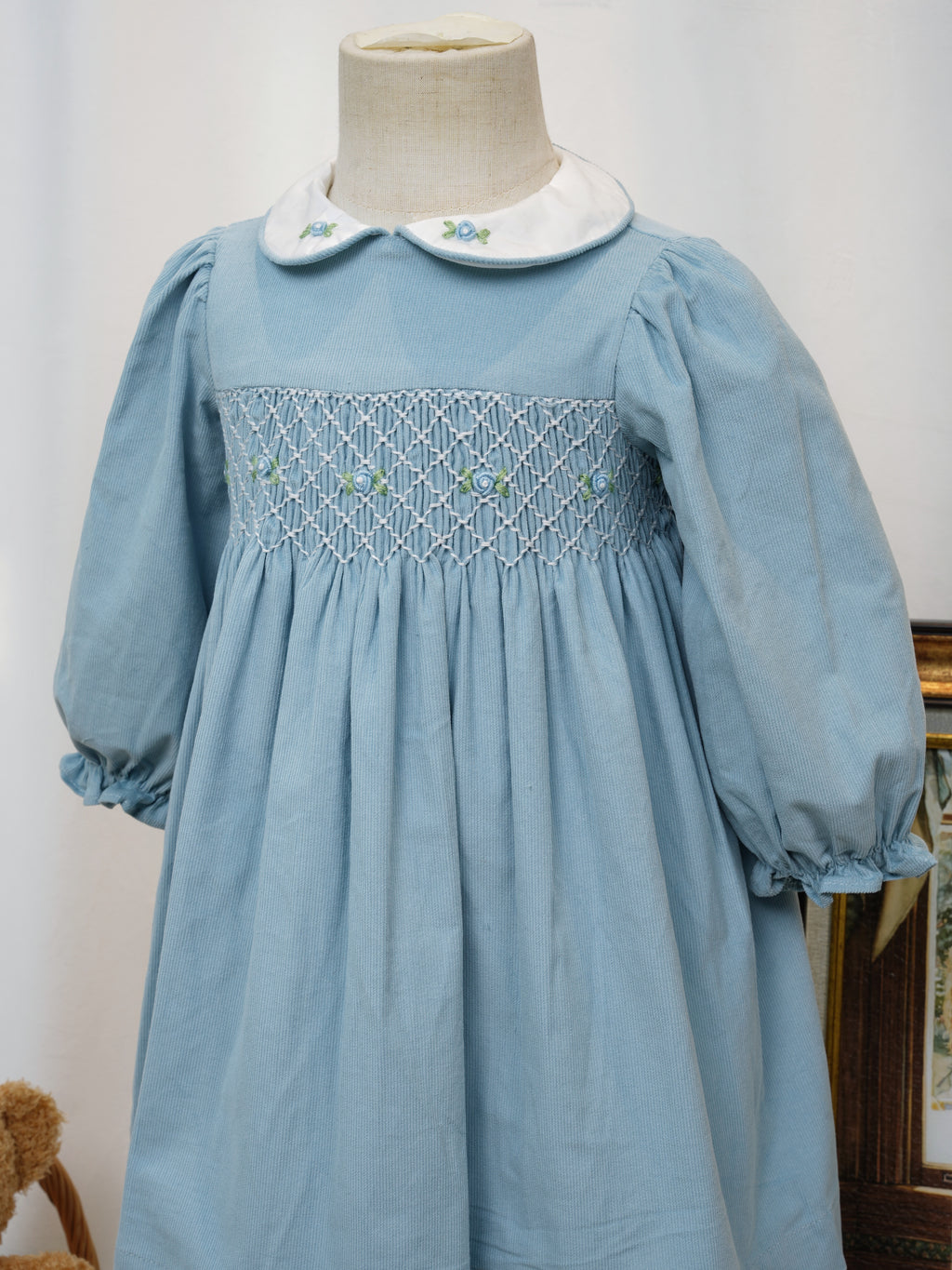 Close-up of hand smocking and floral embroidery on blue dress