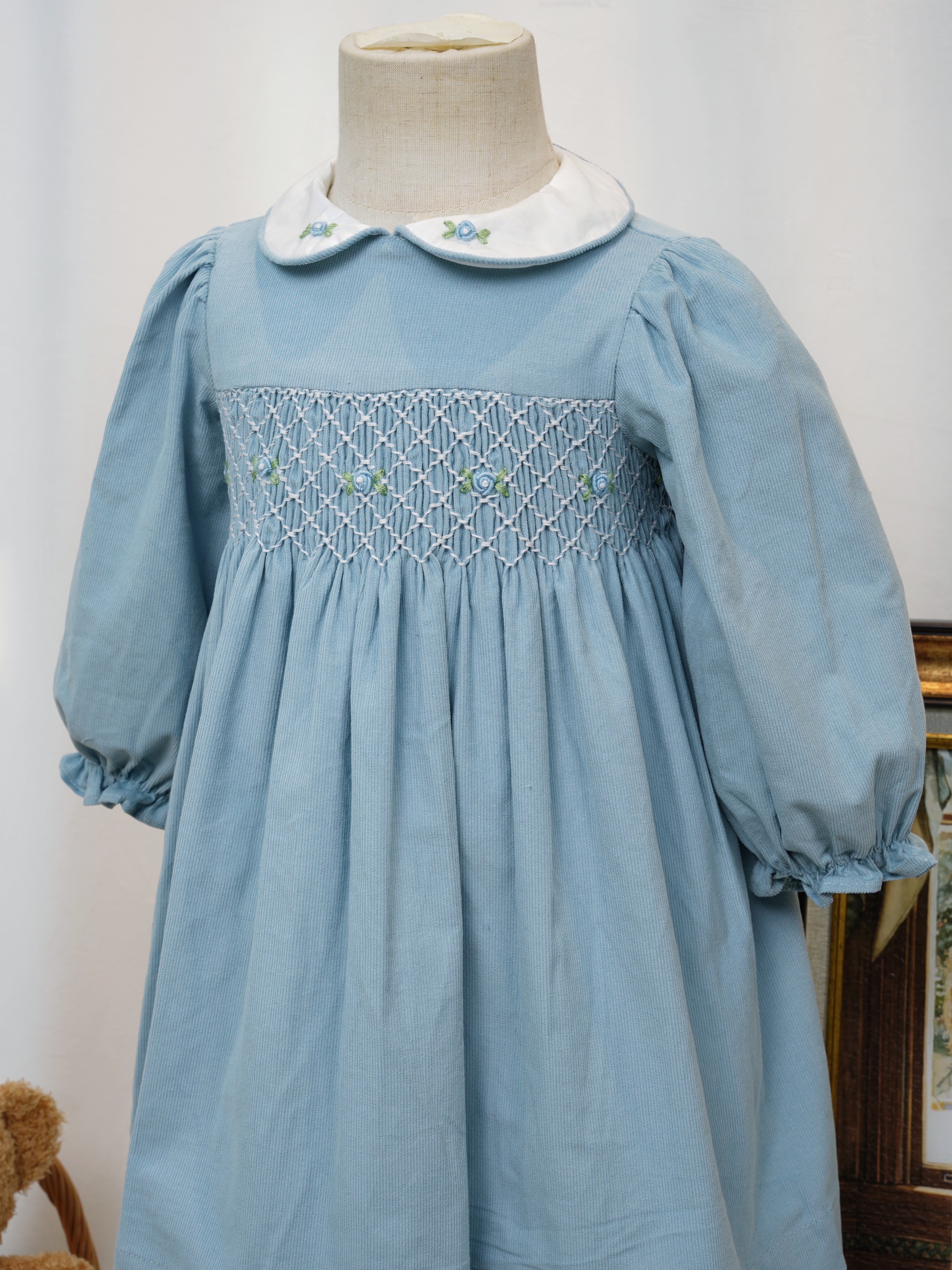 Close-up of hand smocking and floral embroidery on blue dress