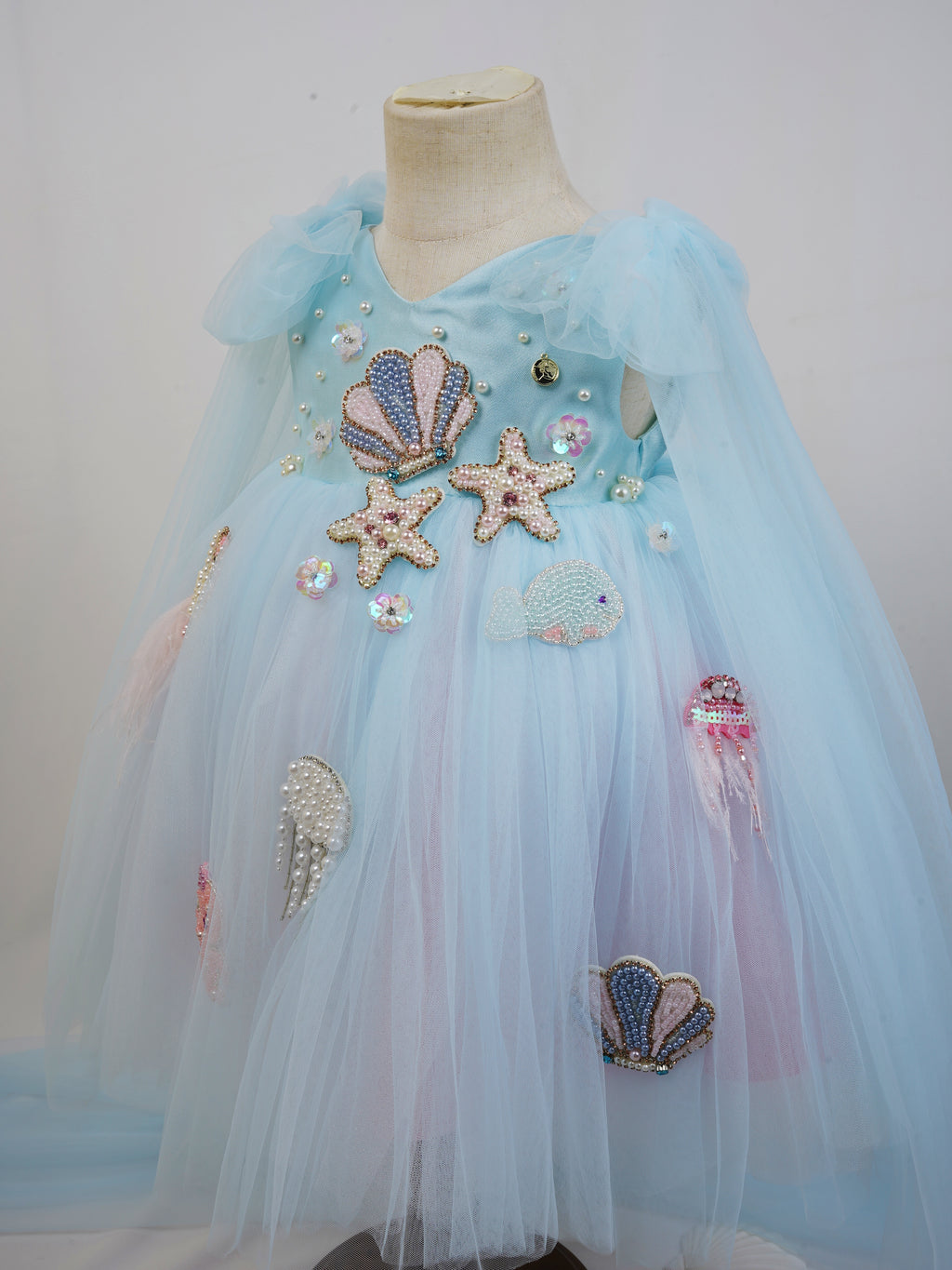 angled view showing shoulder tie cape and layered tulle skirt